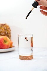 Food natural supplement liquid drops in glass of water with pipette, lifestyle