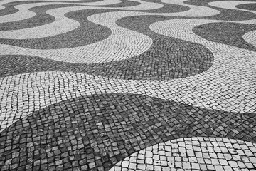 Typical Portuguese mosaic cobble stone paving in Lisbon, Portugal, black and white. - 747597454