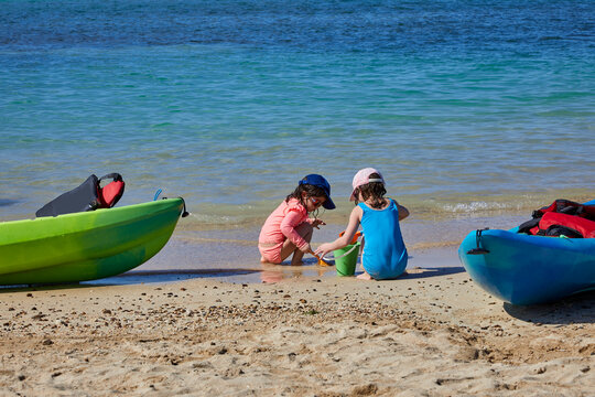 Little girls playing in the sand on a beach on a bright sunny day near the ocean