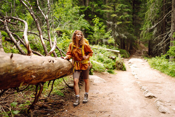 Beautiful traveling woman  in the mountains on a background of a forest. Hiking, active lifestyle....