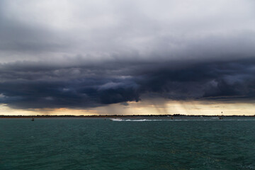 Uninhabited islands of Venetian lagoon and sea with dark stormy sky in background. View from Murano island, Venice, Italy