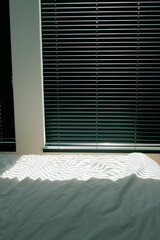 closed black blinds in the morning bedroom, light and shadows movie effect