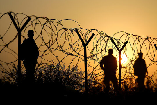 Group of blurred people migrating next to barbed wire