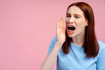 Portrait of young beautiful red haired woman screaming with open mouth isolated