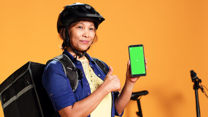 Close up of woman presenting mock up chroma key green screen smartphone. Portrait of courier...