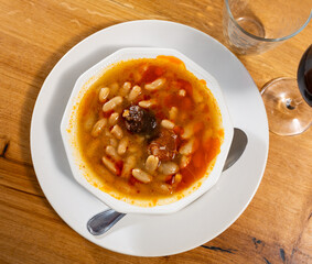 Asturian fabada soup with beans and pork served in bowl to table..