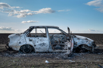 A burned out car. Burnt car in the field. Car fire, vehicle fire due to short circuit. Stolen car...