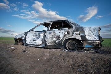 A burned out car. Burnt car in the field. Car fire, vehicle fire due to short circuit. Stolen car...