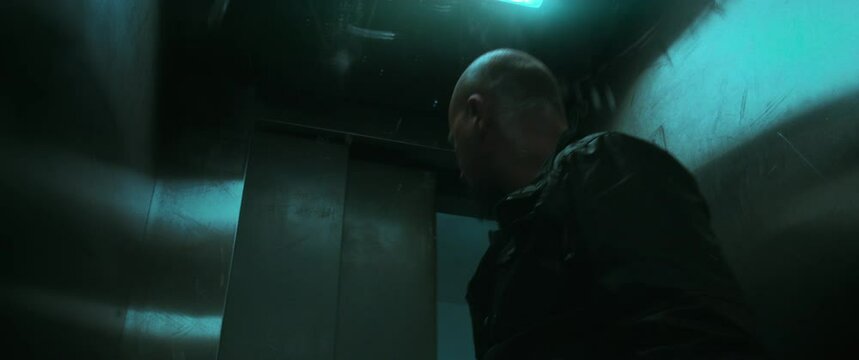 A bald man waits till the elevator door closes