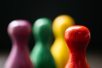 Three pawn-style playing pieces standing together and a red one in a distance from them