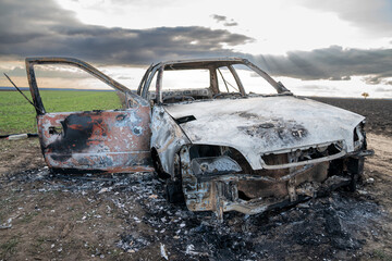 A burned out car. Burnt car in the field. Car fire, vehicle fire due to short circuit. Stolen car...