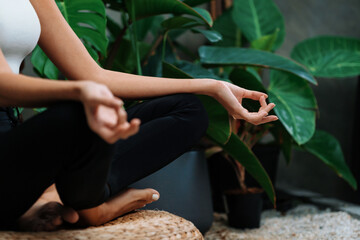 Young woman doing morning yoga and meditation in natural garden with plant leaf, enjoying the solitude and practicing meditative poses. Mindfulness activity and healthy mind lifestyle. Blithe