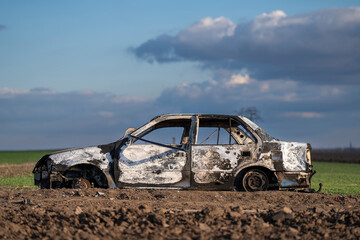 A burned out car. Burnt car in the field. Car fire, vehicle fire due to short circuit. Stolen car...
