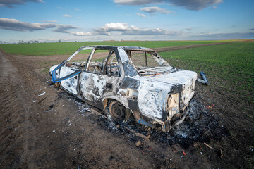A burned out car. Burnt car in the field. Car fire, vehicle fire due to short circuit. Stolen car...