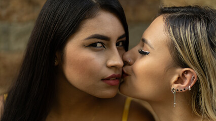 Obraz premium Sensual closeup portrait of two multiracial girls kissing while one of them sees the camera