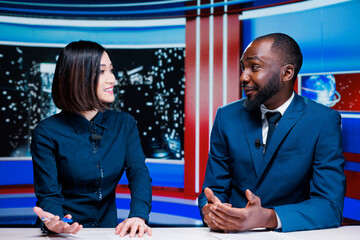 Two reporters broadcasting live information on international television channel, addressing all...