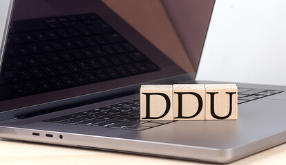 DDU word on wooden block on laptop, business concept