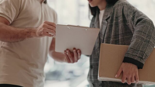Delivery service concept with person receiving a package and signing a clipboard