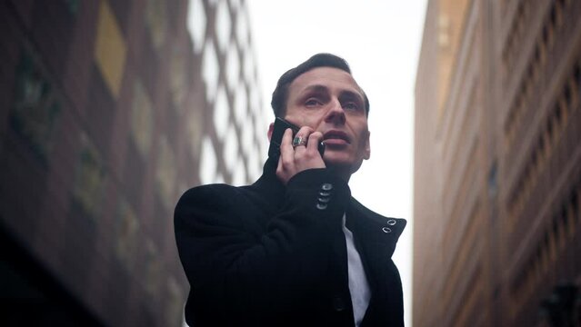 Businessman having a phone call outside between buildings