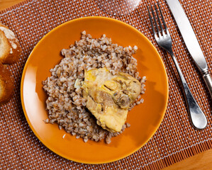 Boiled buckwheat in a bowl with chicken thighs. Dinner table, healthy food concept © JackF