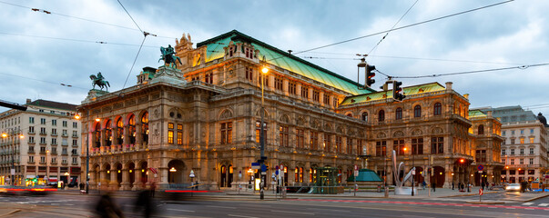 Fototapeta na wymiar Picturesque view of central avenue of Vienna and illuminated impressive building of famous State Opera at cloudy winter twilight, Austria.