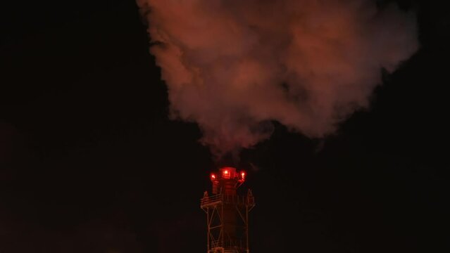 Industrial furnace chimney at night. Red aviation obstruction lighting.