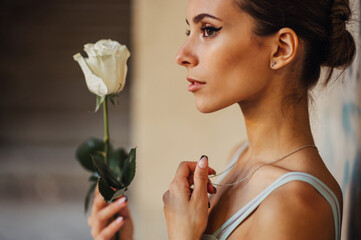 Close up of prima ballerina holding a white rose in rustic building.