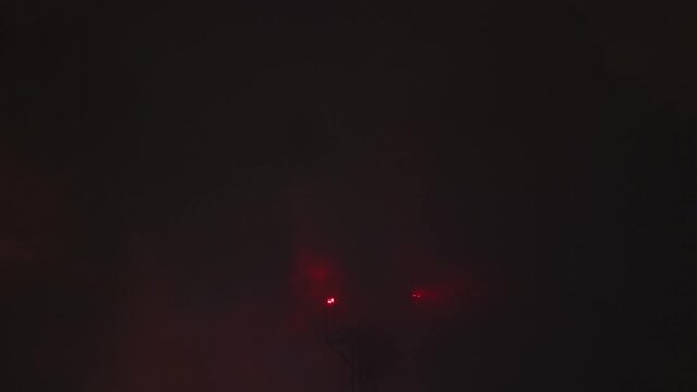 Close-up industrial furnace chimney in a steam of cooling towers. Red warning beacon. Night scene at extremely low temperature.