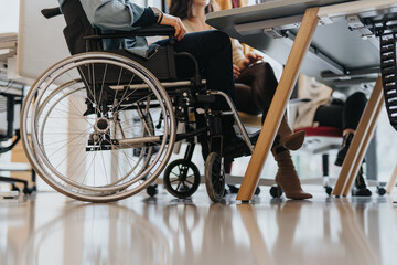 Cropped photo of handicapped employee in wheelchair attending meeting gathered at table.