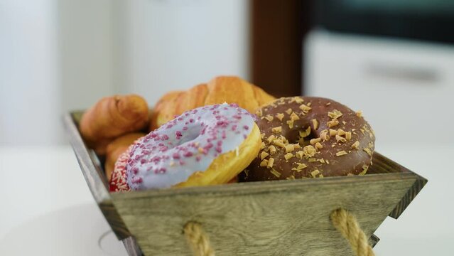 Croissants and donuts in wooden basket rotate in the kitchen. Morning dessert