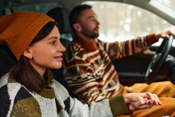 Side view of happy woman holding husbands hand while travelling by car on winter day
