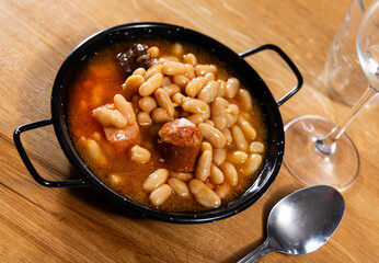 Asturian fabada soup with white beans and blood sausage served in bowl