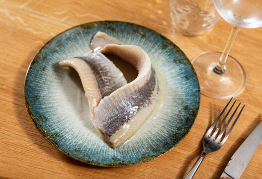 There is of salted herring appetite sild fillet seasoned on white ceramic plate. Traditional Russian snack