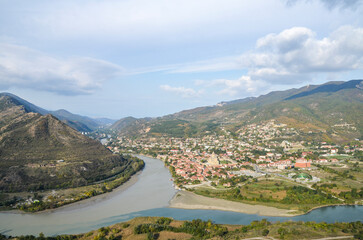 Fototapeta premium Historic center of the Mtskheta town with vibrant buildings and Svetitskhoveli Cathedral nestled at foot of the mountains at the confluence of the Mtkvari (Kura) and Aragvi rivers. Georgia