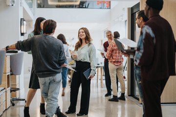 Businesspeople in a modern office space are engaging in a relaxed, informal networking session, exuding a friendly and collaborative atmosphere.