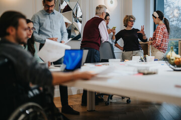 Inclusive work environment captured as a diverse team engages in a collaborative brainstorming session, showcasing teamwork and communication in an office setting with a person in a wheelchair.
