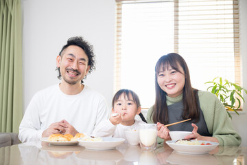 ダイニングで食卓を囲む幸せな家族のイメージ　カメラ目線の笑顔