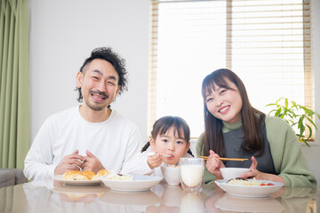 Obraz na płótnie Canvas Image of a happy Asian (Japanese) family around the table in the dining room Smiling for the camera