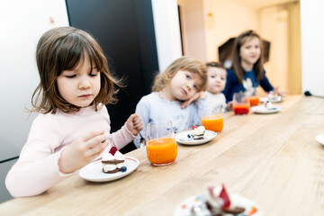 Quattro bambine fanno la colazione con dolce e spremuta