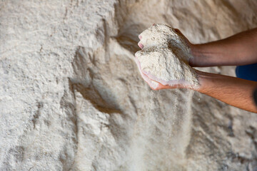 Male hands holding handful of soy flour on background of large pile. Healthy organic protein...