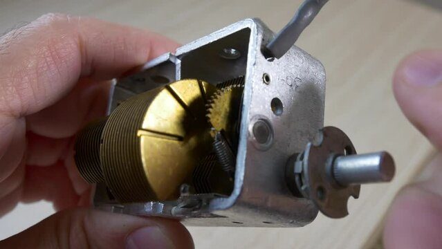 Double gang air variable capacitor with reduction gear. Hand turns the rotor of a tube radio capacitor for station tuning.
