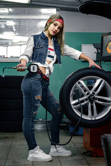 Young girl at a car service holds a pressure gauge and measures the pressure in the wheel..