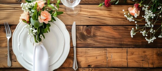 An elegant table decor featuring a white plate adorned with a beautiful bouquet of flowers, placed on a wooden table with folded napkin and cutlery.