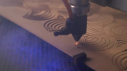 Close-up of industrial laser heating plywood and cutting through wood