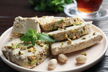 Pieces of tasty halva with pistachios and mint on table, closeup