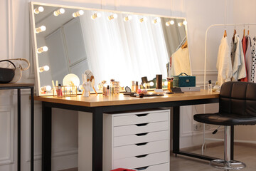 Makeup room. Stylish dressing table with mirror, chair and clothes rack
