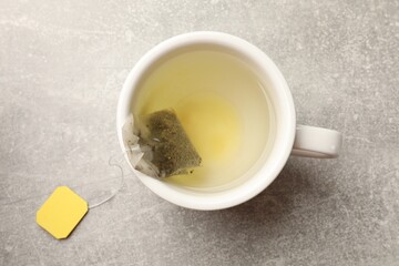 Brewing tea. Cup with tea bag on light table, top view