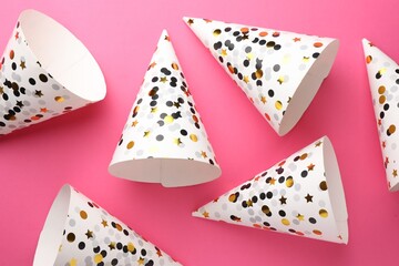 Beautiful party hats on pink background, top view