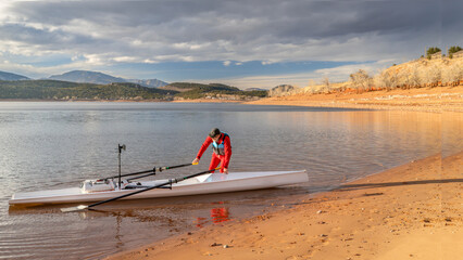senior rower is rigging his rowing shell on a shore of Carter Lake in northern Colorado in winter scenery