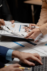 A group of three businesspeople are working together to calculate the company's numbers, employees are meeting about an important document that has many numbers that must be carefully calculated.